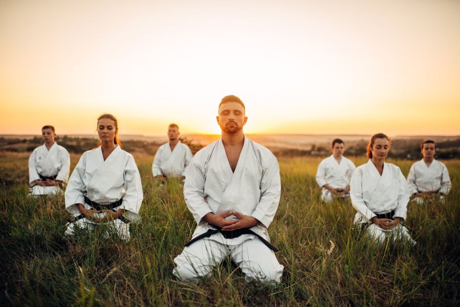 Karatékas en méditation en extérieur, au coucher du soleil